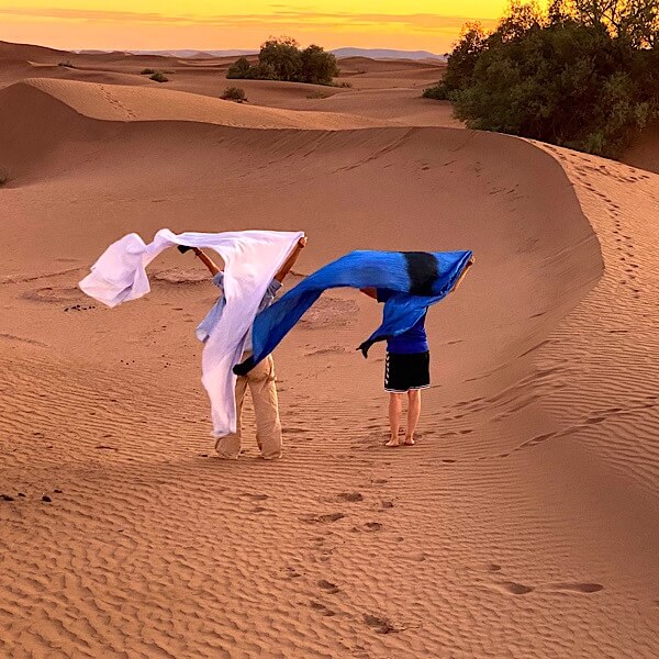 Zwei Frauen mit Tüchern im Wind in der Wüste. 
