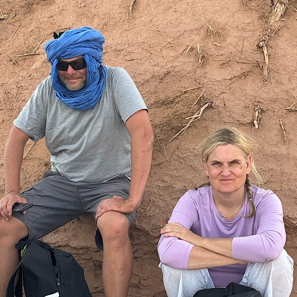 Mann und Frau sitzen im Schatten in der Wüste. 