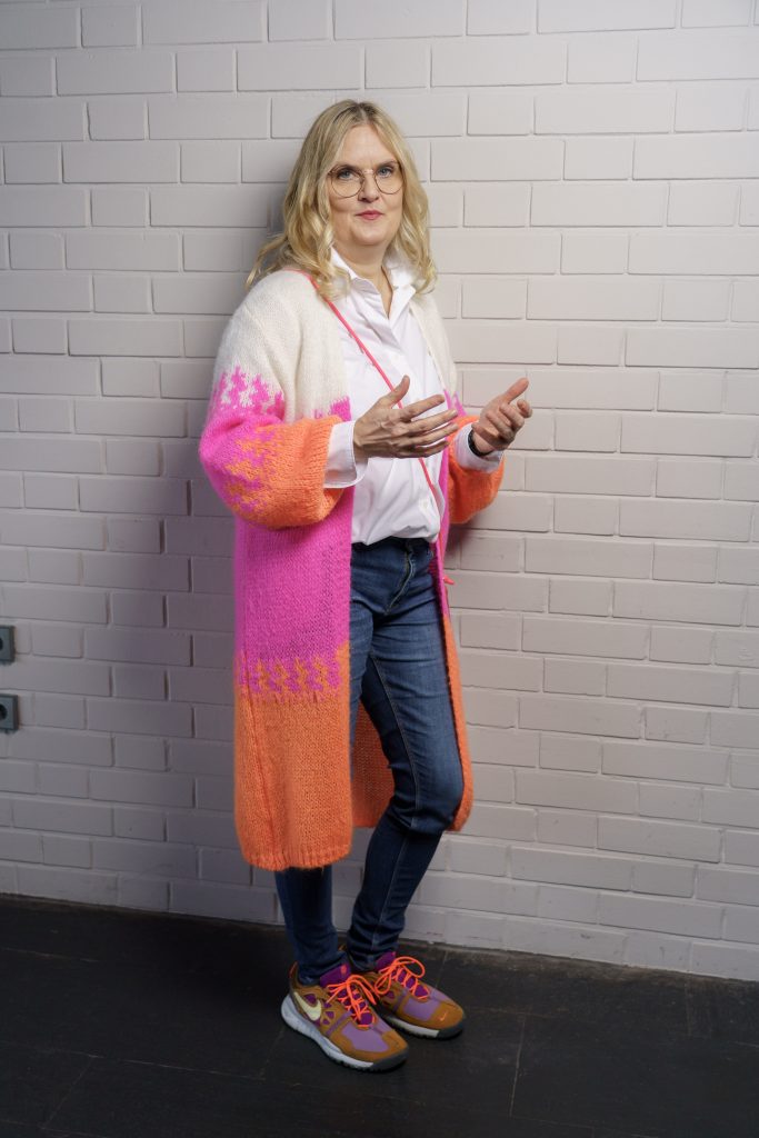 Jutta Büttner steht an der Wand und gestikuliert lässig