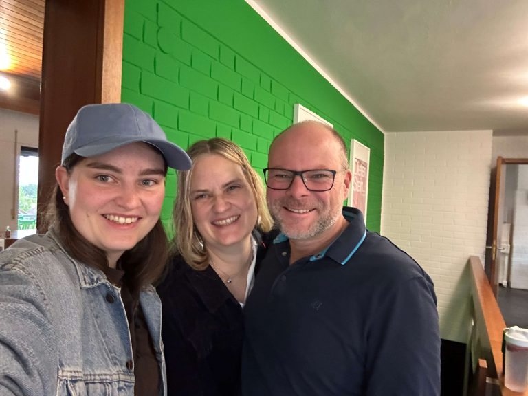 Drei Menschen stehen vor einer grünen Wand