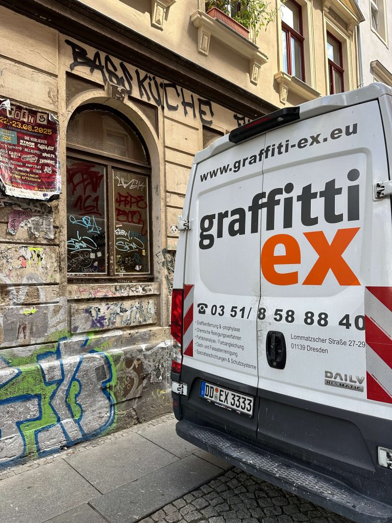 Malerauto mit Aufschrift graffitti-ex vor einer Hauswand mit Graffitti