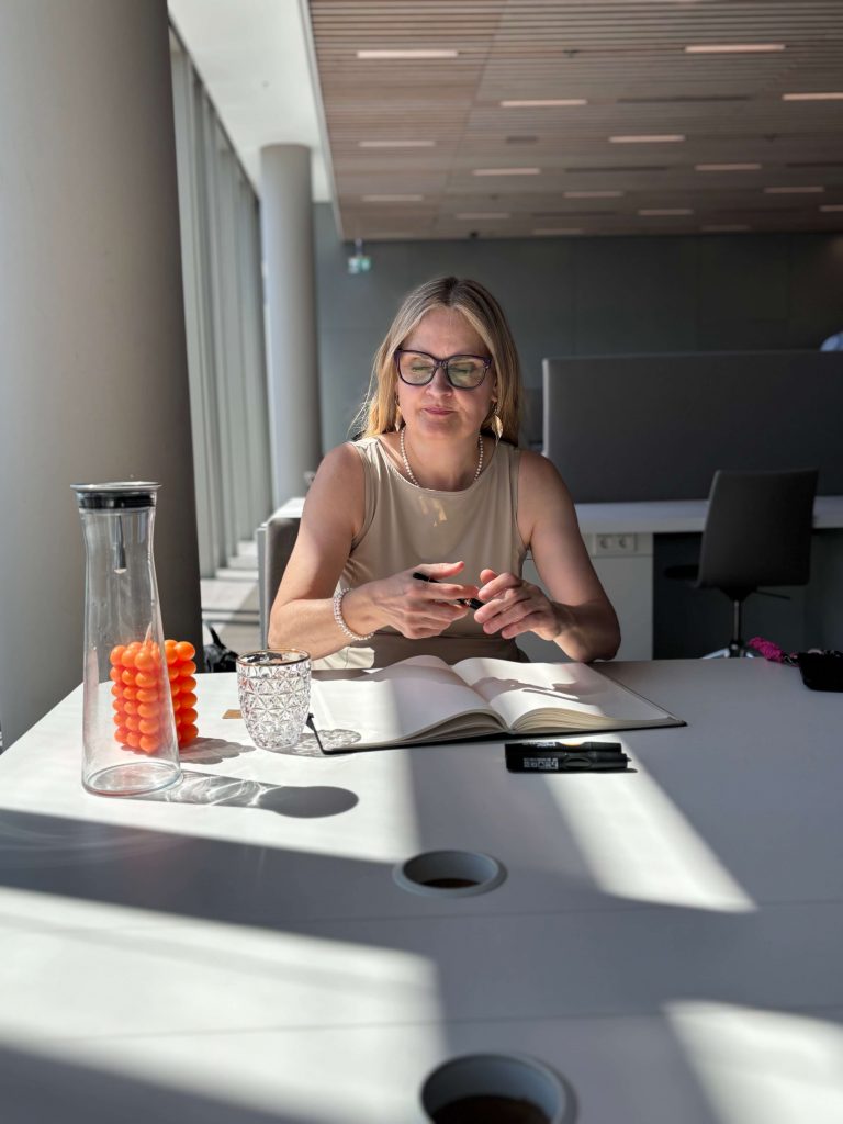 Frau an einem Tisch mit Wasserflasche und Notzibuch