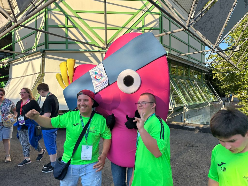 Zwei Menschen vor dem Maskottchen von Special Olympics