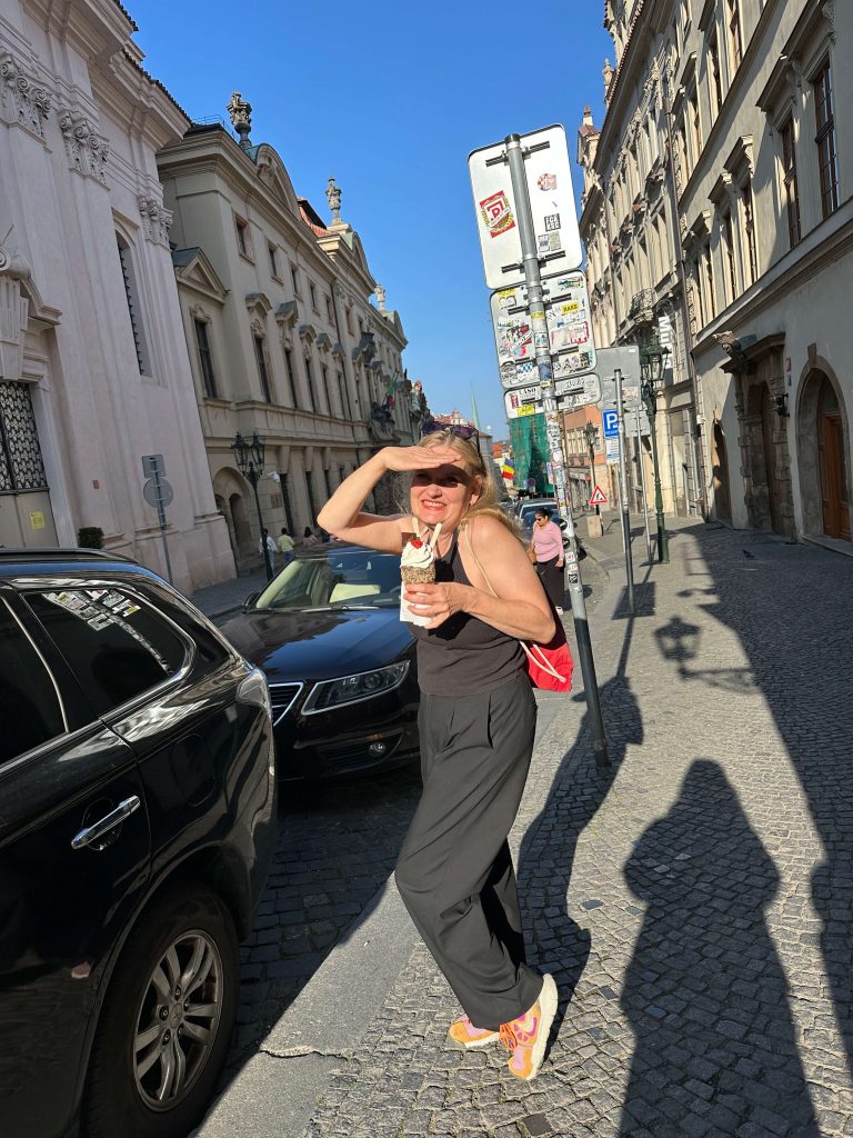 Frau steht an der Straße und hält die Hand an die Stirn, damit die Sonne weniger blendet.