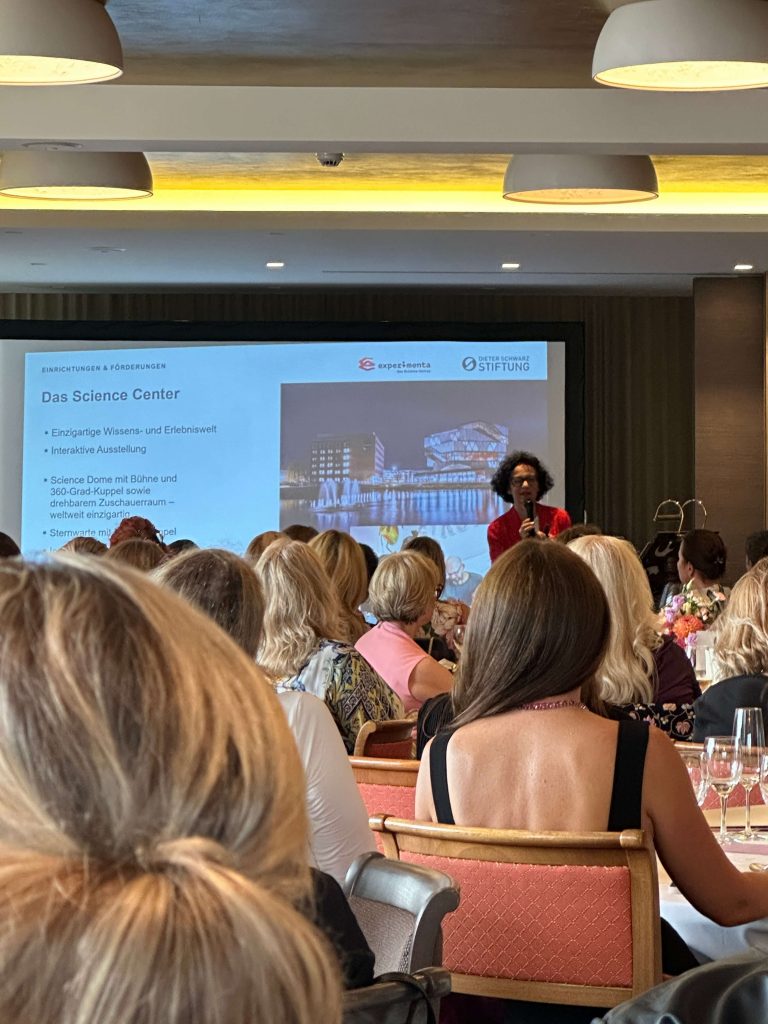 Zuhörerinnen blicken auf die Vortragende und sind von hinten zu sehen