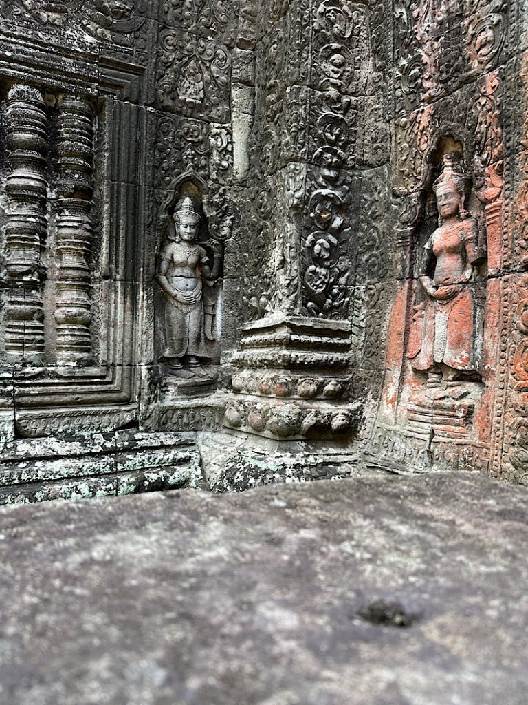 Relief einer Tänzerin in Sandstein aus Angkor Wat, Siam Reap, Kambodscha. Es ist auc hncoh eine Scheintür zu sehen und eine weitere Tänzerin.