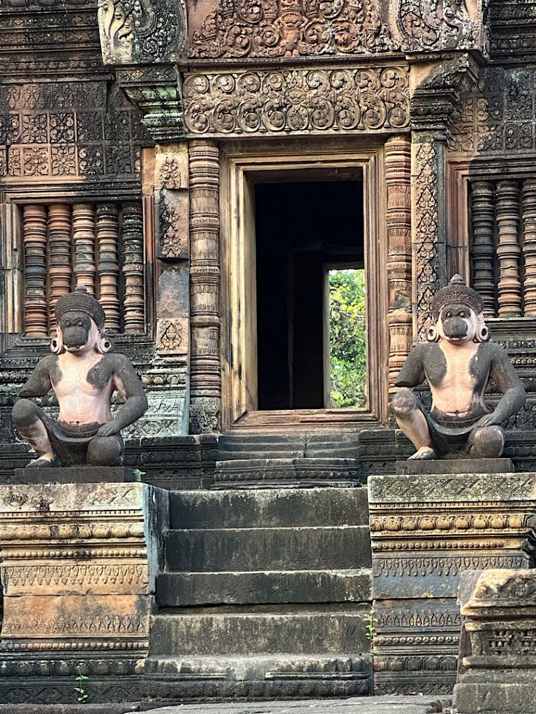 Türöffnung zu einem Tempel in Angkor Wat, Kambodscha. Der Türrahmen ist verziert. Davor sind zwei Affensoldaten dargestellt. Alles ist aus Sandstein.