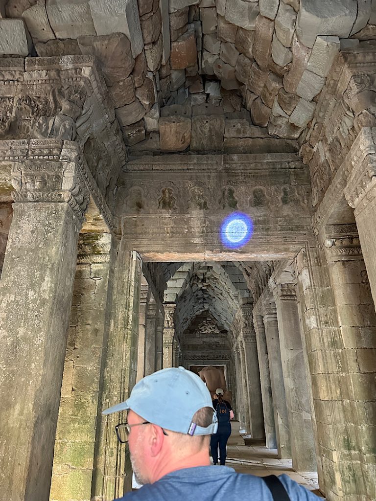 Ein Mann schaut sich die Reliefs in Angkor Wat an. Eine Taschenlampe leuchtet auf eine bestimmte Stelle des Reliefs.