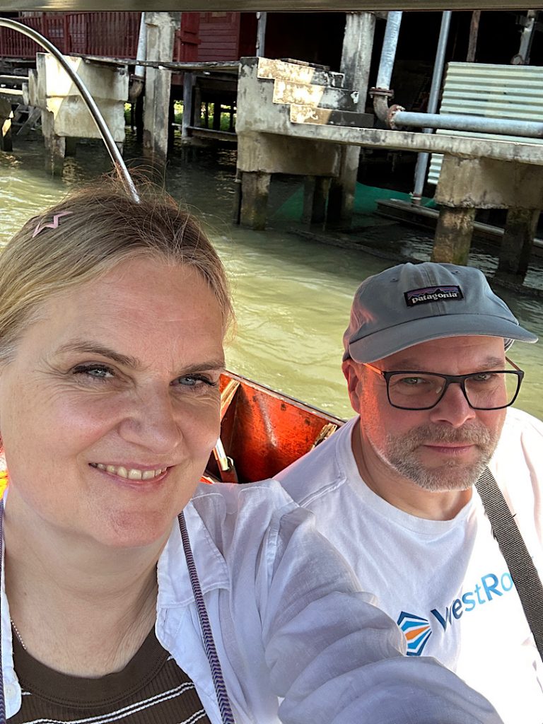 Ein Mann und eine Frau sitzen in einem Boot. Sie lächeln in die Kamera.