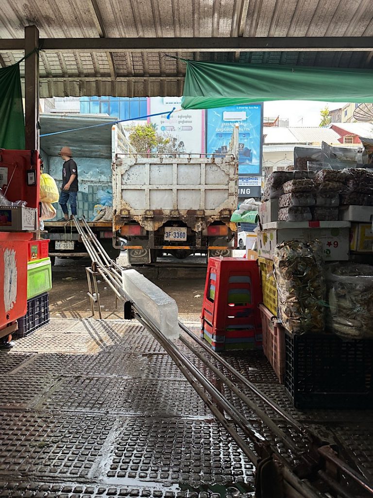 Von einem LKW führt eine Rutsche für Eisblöcke in die Markthalle