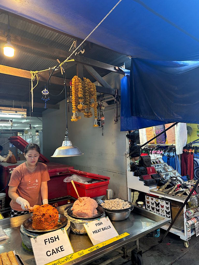An einem Marktstand bietet eine Frau Fisch an