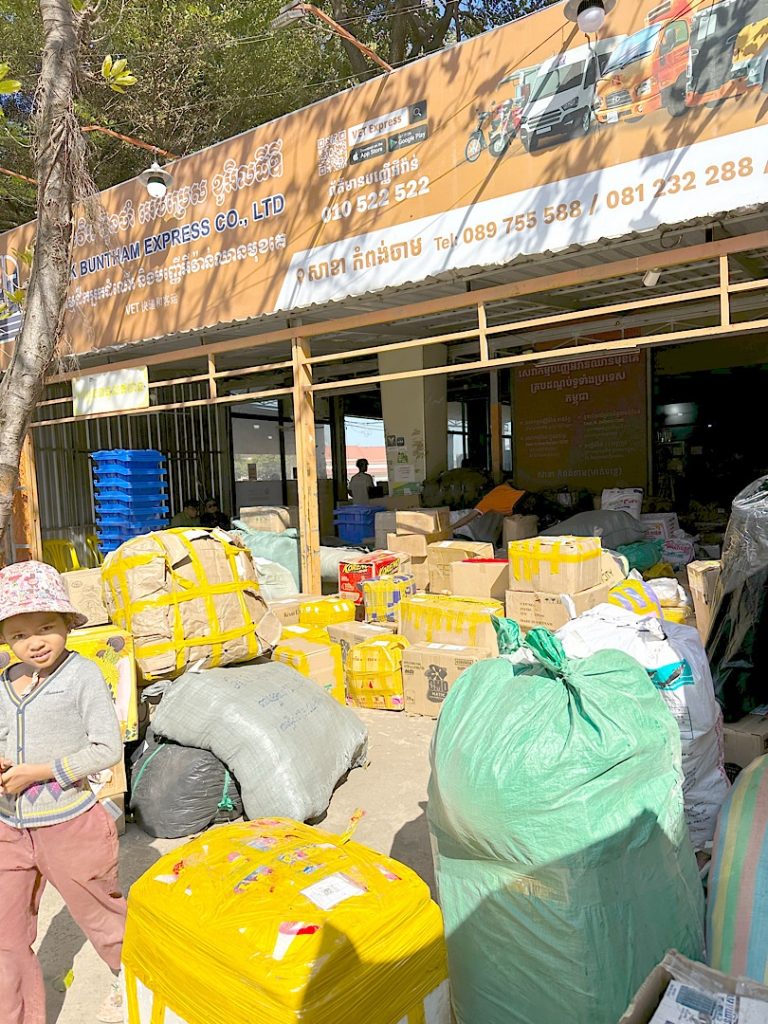 Es sind viele Kästen und Tüten zu sehen. Sie liegen in einer offenen Halle und füllen auch den Gehweg davor.