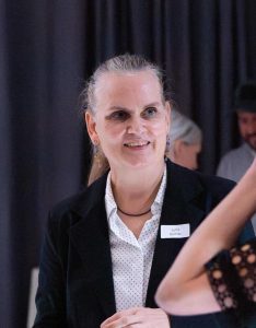 Frau in Anzug spricht mit einer Person.